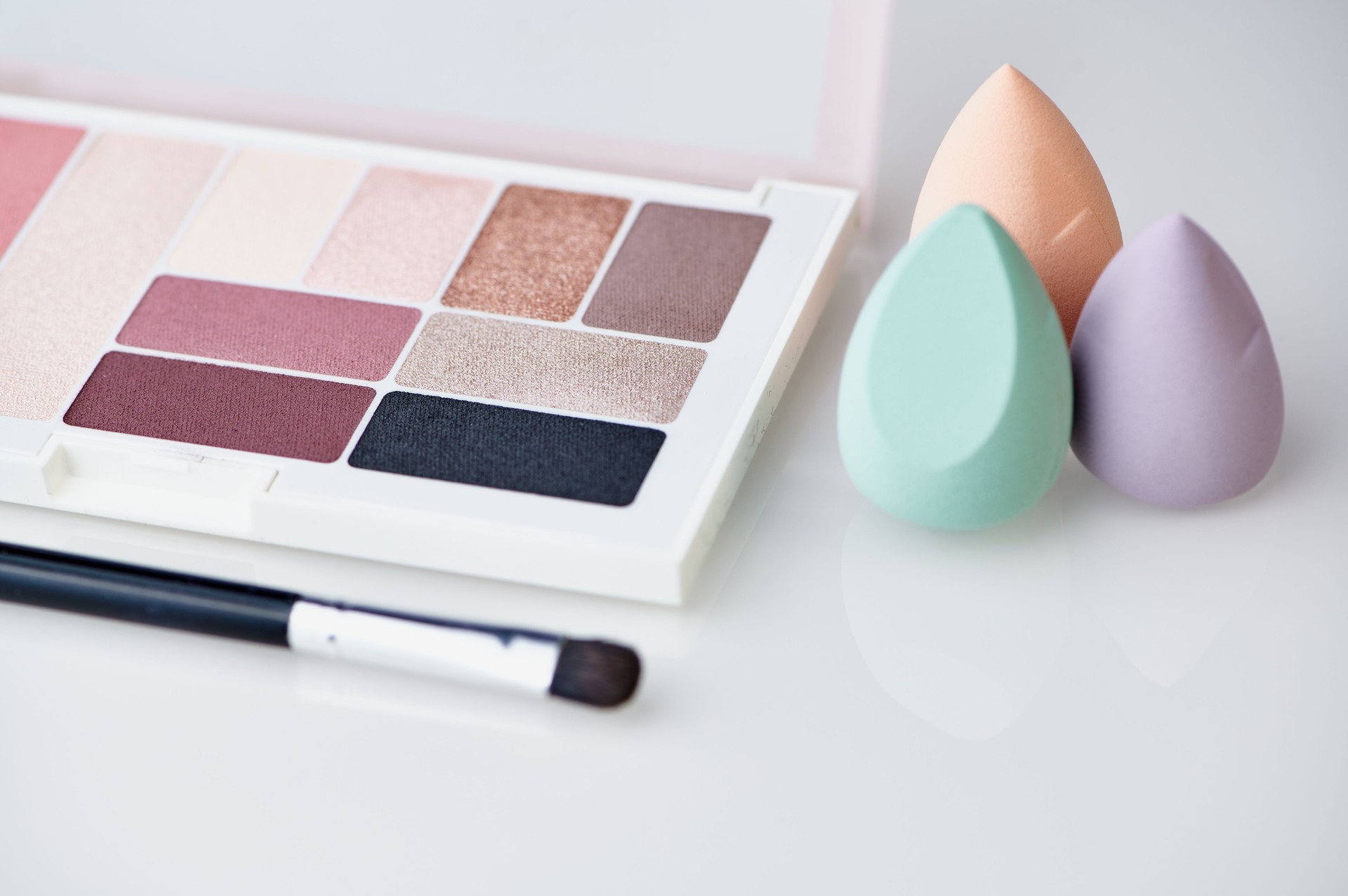 make-up blender sponges and eyeshadow palette on white background
